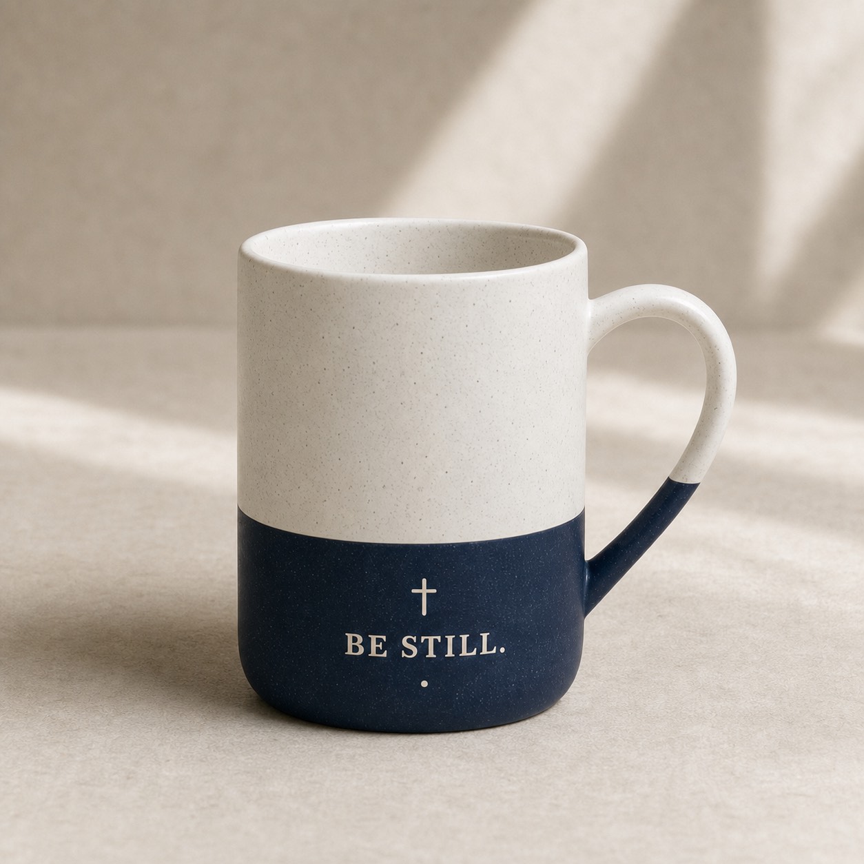 A navy stoneware mug engraved with the words Be Still.